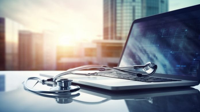 A stethoscope on a laptop with a background of a sun shining in between buildings.